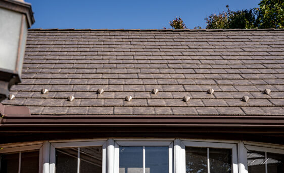 Closeup photo of a brick home with ProVia's Lodgestone slate metal roofing, a brown color