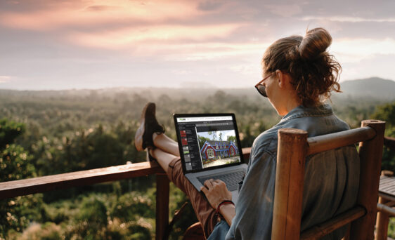 Woman on a laptop outside using ProVia's Design Center home exterior design tools to design home exterior solutions.