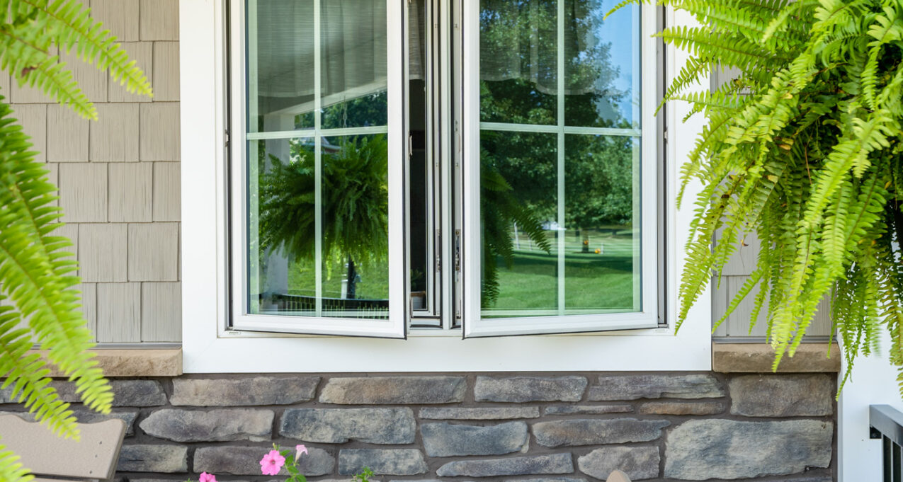 Opened Endure™ white casement windows with cottage grids on a porch; example of casement windows in ProVia's window gallery