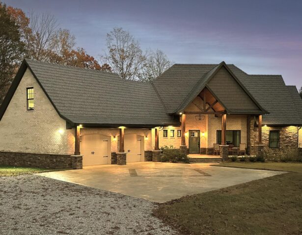 Photo of a home at dusk with ProVia's Larkstone Slate metal roofing and Shawnee Dry Stack stone