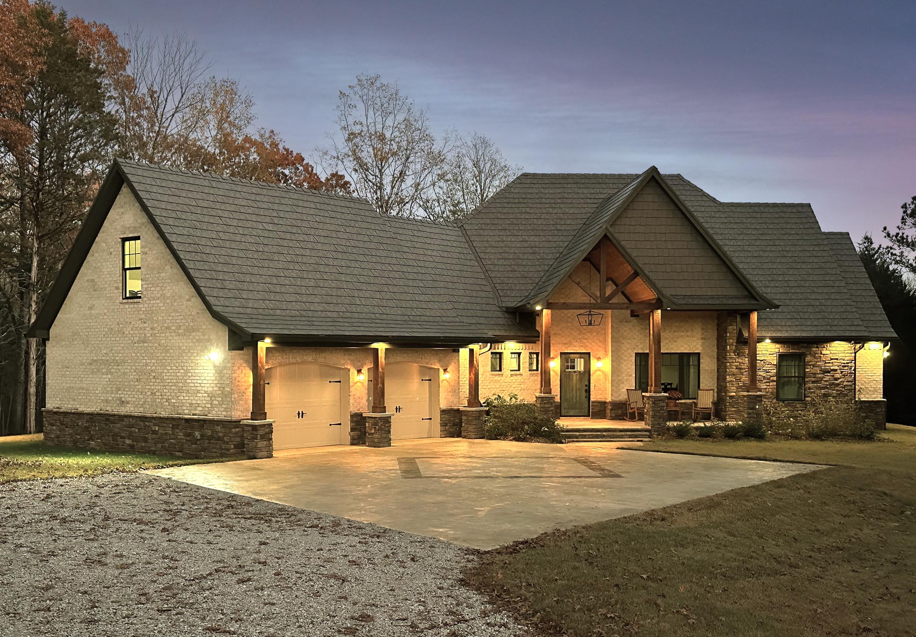 Photo of a home at dusk with ProVia's Larkstone Slate metal roofing and Shawnee Dry Stack stone