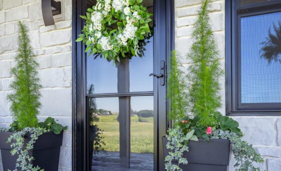 Spectrum Full View glass storm door in Coal Black over a Signet fiberglass entry door, which contrasts nicely with white stone on a home exterior