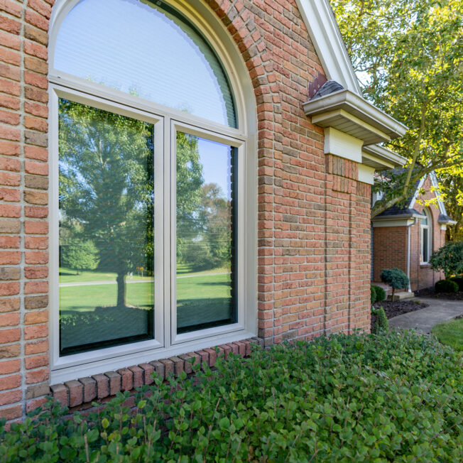 Exterior view of Aeris™ Casement and Shaped Windows in Sandstone on a brick home