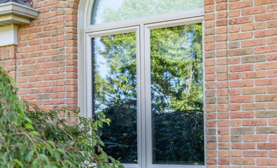 Aeris arch shaped windows in the color beige on a brick home