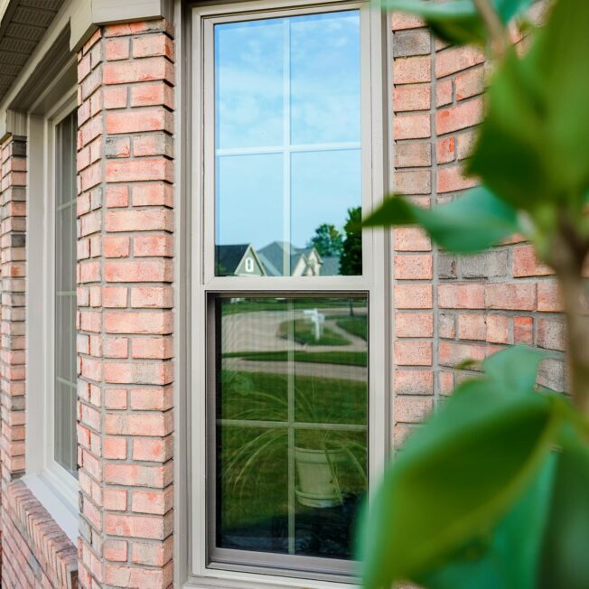 Outside view of Aeris™ Double Hung Windows in Sandstone with Colonial Grids on a brick home