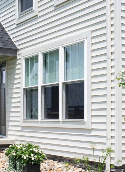 HeartTech vinyl siding in the color White on a two-story home with a portico; main image on ProVia's vinyl siding accessories page