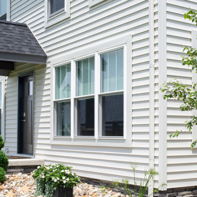 HeartTech vinyl siding in the color White on a two-story home with a portico; main image on ProVia's vinyl siding accessories page