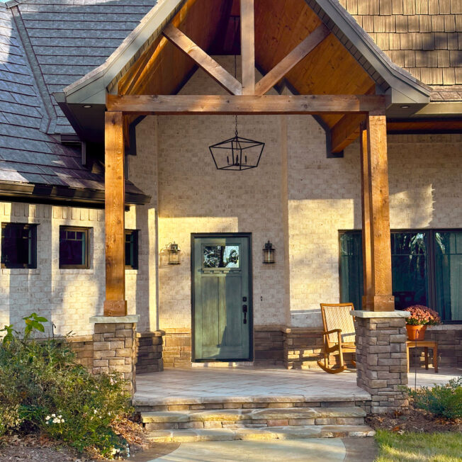 Brick home with a timber frame entrance, Signet fiberglass door in Rustic Sage, and Shawnee dry stack stone veneer on the bottom of the home and timber frame columns.