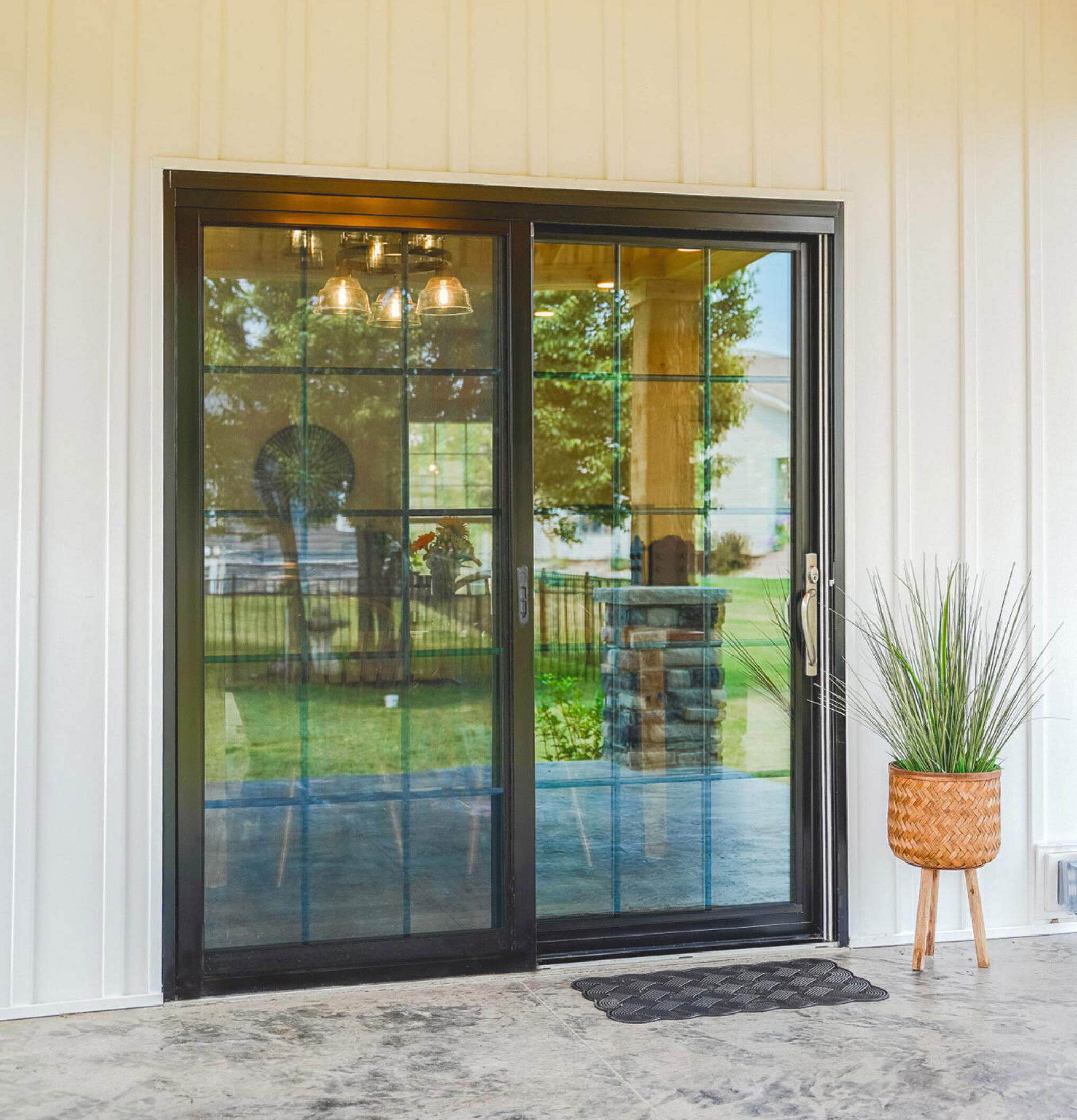 Exterior view of a ProVia Endure™ Patio Door in Black with Colonial Grids on a house with white siding