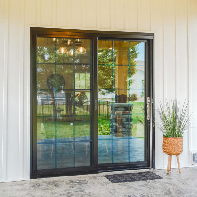Exterior view of a ProVia Endure™ Patio Door in Black with Colonial Grids on a house with white siding