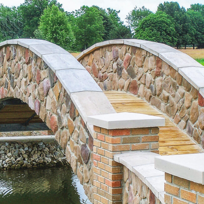 Arched stone bridge over a stream featuring Shenandoah field stone veneer