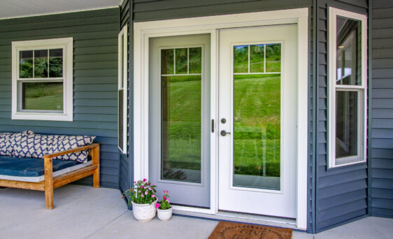 Home with dark blue vinyl siding and a white hinged patio door