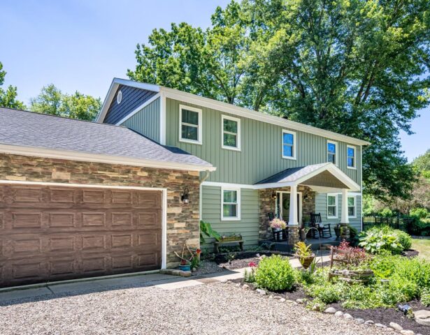 Two-story home with green ProVia vinyl siding blended with manufactured stone veneer in a blend of browns and tans