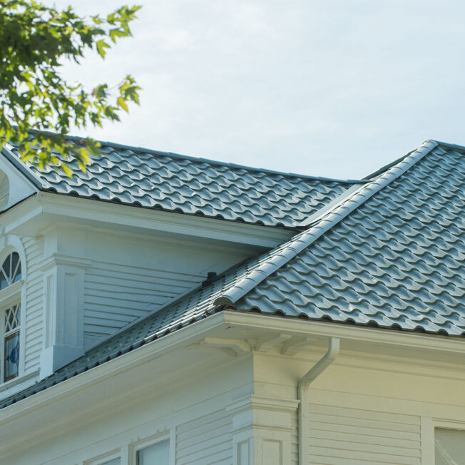 Closeup view of a home with ProVia's new metal barrel tile roof in Jade, example of metal roofing that looks like clay tile