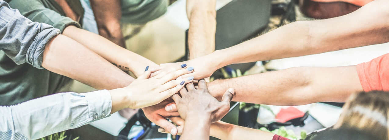 Stock image of team member hands overlapping, representing team work or collaboration