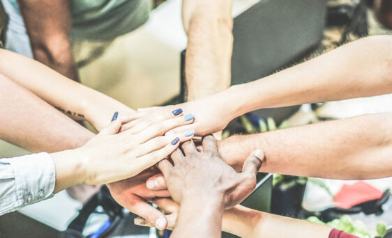 Stock image of team member hands overlapping, representing team work or collaboration