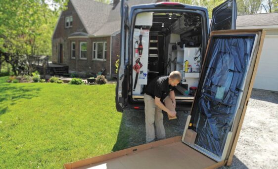 Image of a installer getting ready to install one of ProVia's prehung exterior doors outside a home, showing the box and all that's included with a ProVia pre-hung exterior door