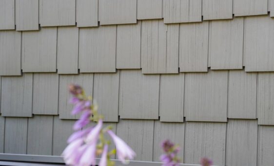 Closeup of ProVia Harbor Mill Staggered Shingle siding on a home with purple flowers in front of it