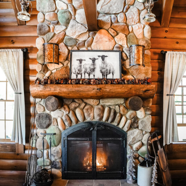 Cozy interior image of a log cabin fireplace with ProVia Mountain River Rock manufactured stone on a fireplace