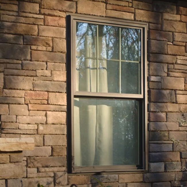 Closeup exterior image of ProVia Aeris™ Double Hung Windows in Classic Bronze with Cottage Grids